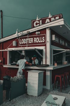 A vibrant street view of a classic lobster roll stand with two adults enjoying a meal.