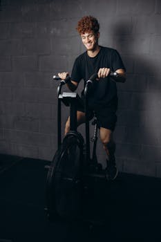 Man enjoying workout on a stationary exercise bike indoors, wearing sportswear.