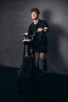 Smiling man working out on a stationary bike in a gym setting, embracing fitness and wellness.