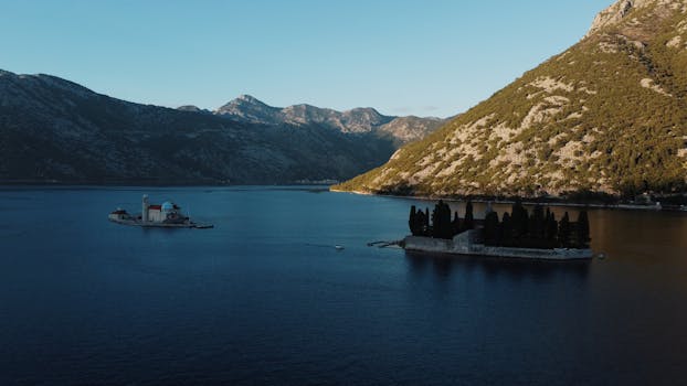 A stunning aerial view of the Bay of Kotor featuring Our Lady of the Rocks and Saint George Island at sunset.