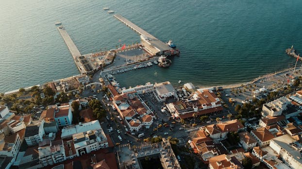 Aerial shot of Kuşadası harbor in Türkiye showcasing the waterfront, cityscape, and marina at golden hour.