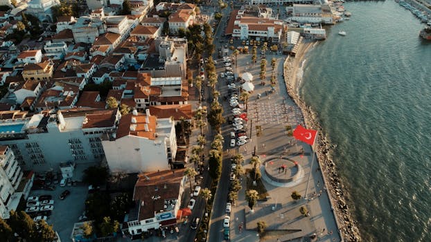 Stunning aerial view of Kuşadası, Türkiye, featuring the waterfront and urban architecture at golden hour.