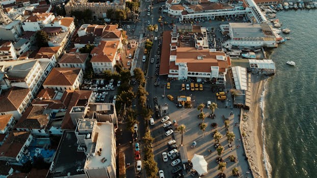 Aerial view of Kuşadası, a vibrant coastal city in Türkiye, during golden hour with waterfront and urban architecture.