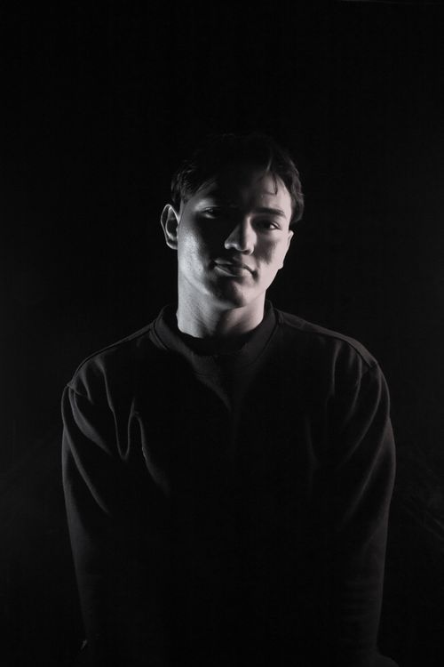 Free Dramatic black and white portrait of a man with strong shadows and soft lighting, creating a mysterious atmosphere. Stock Photo