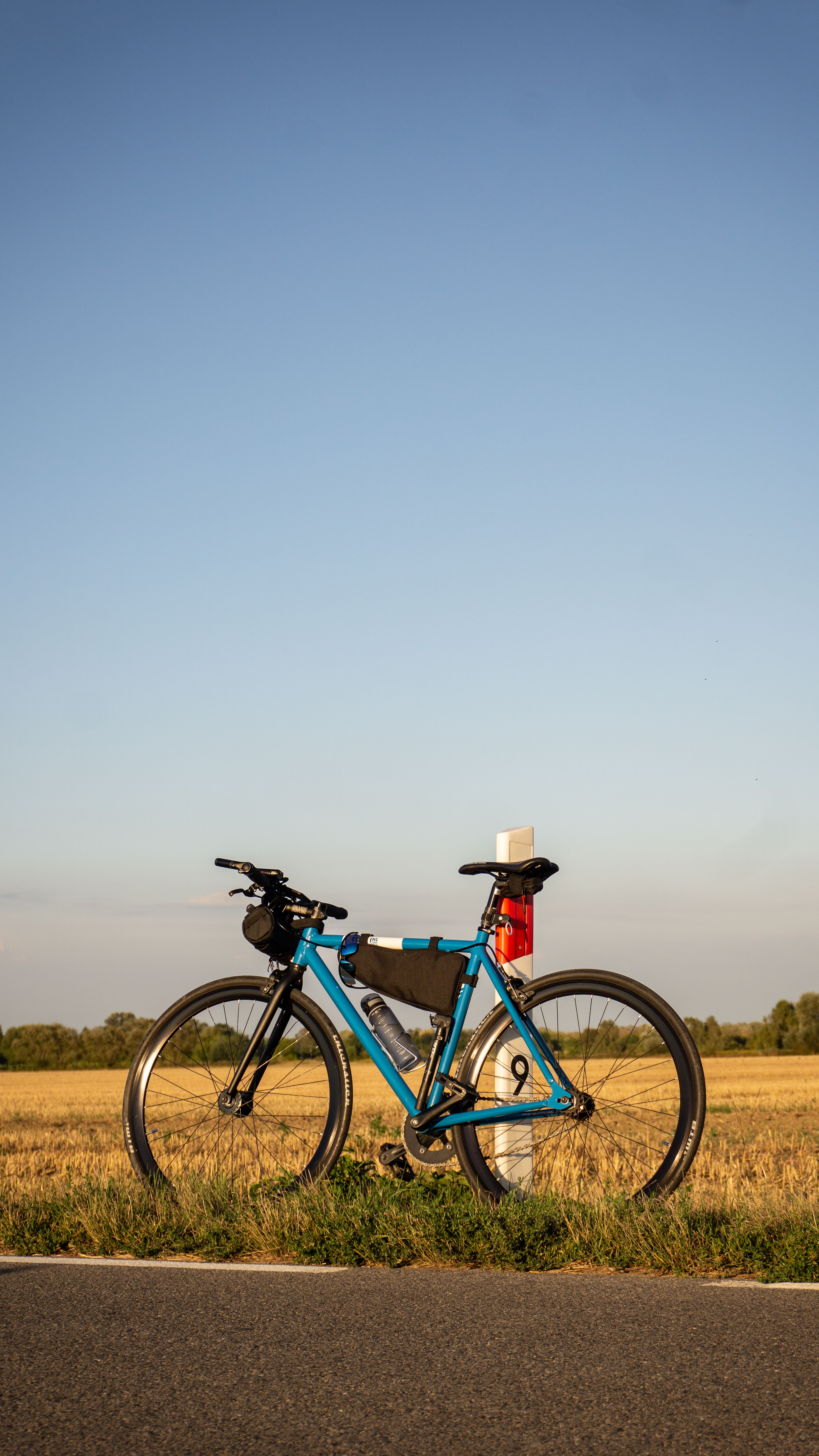 A blue bicycle on a countryside road during a summer sunset in Warsaw, Poland.