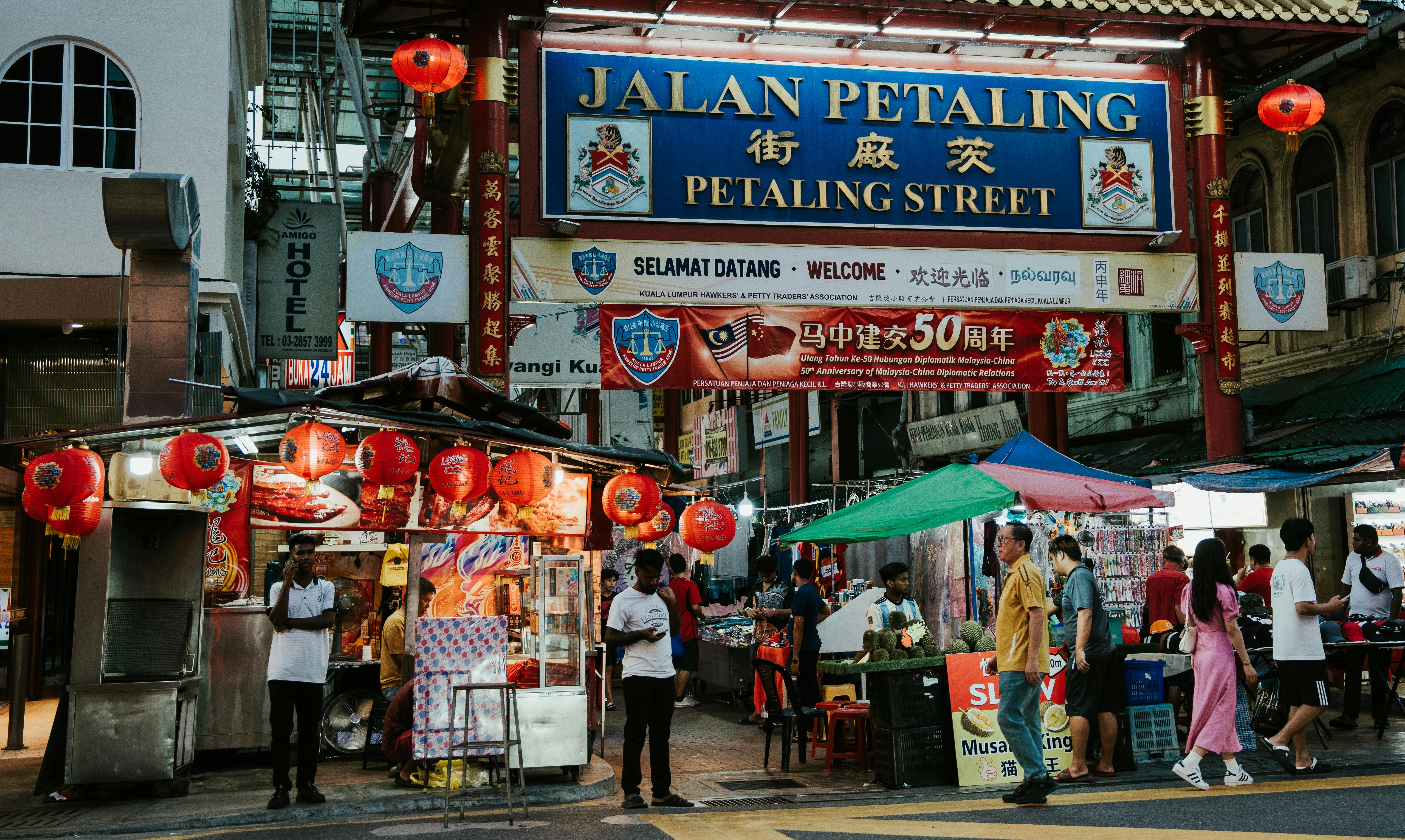 a street with people walking and a sign that says tian petaling street