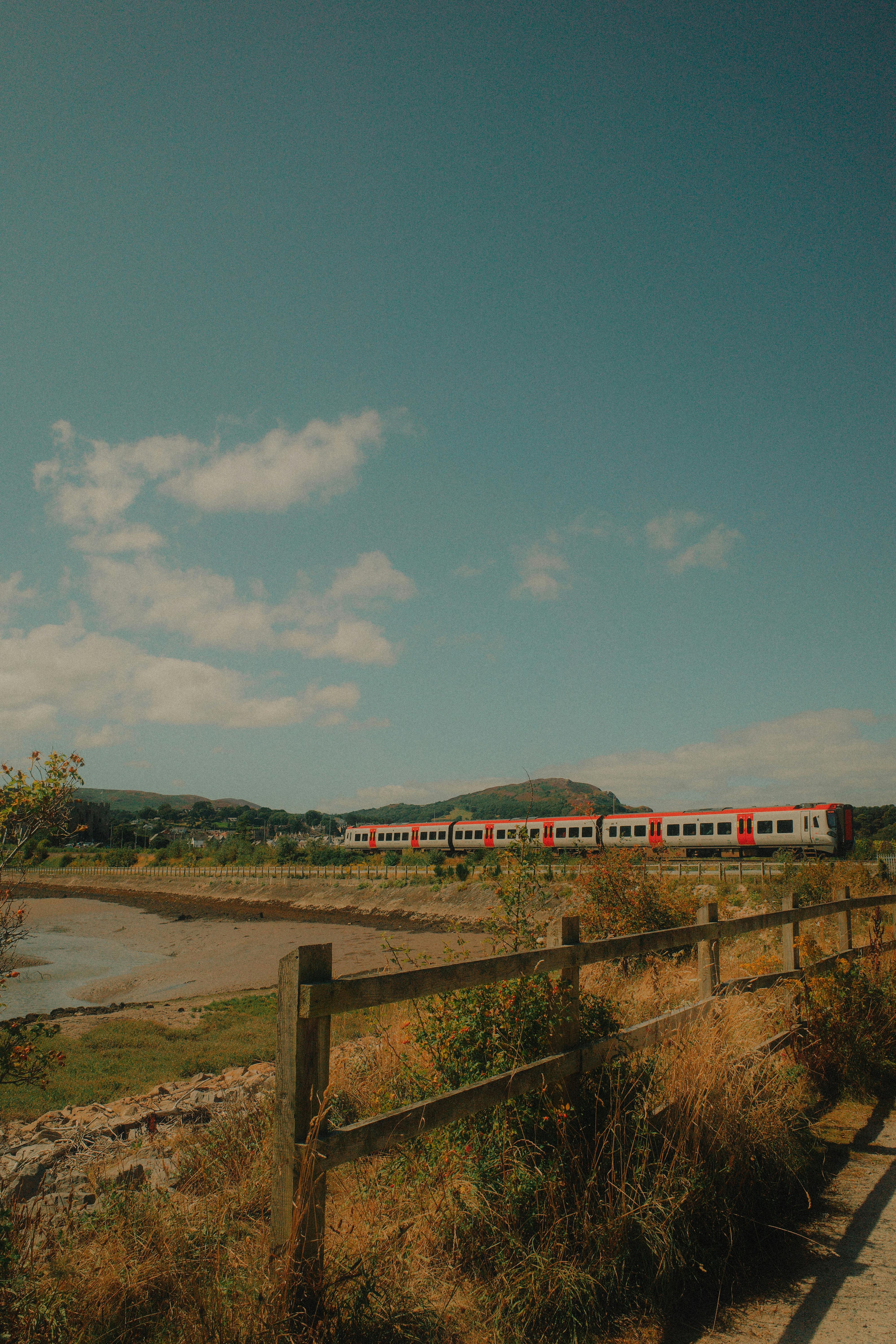 A vibrant train traveling through the picturesque countryside of Conwy on a sunny day.