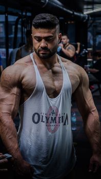 Intense portrait of a muscular bodybuilder training in a gym setting, showcasing strength.