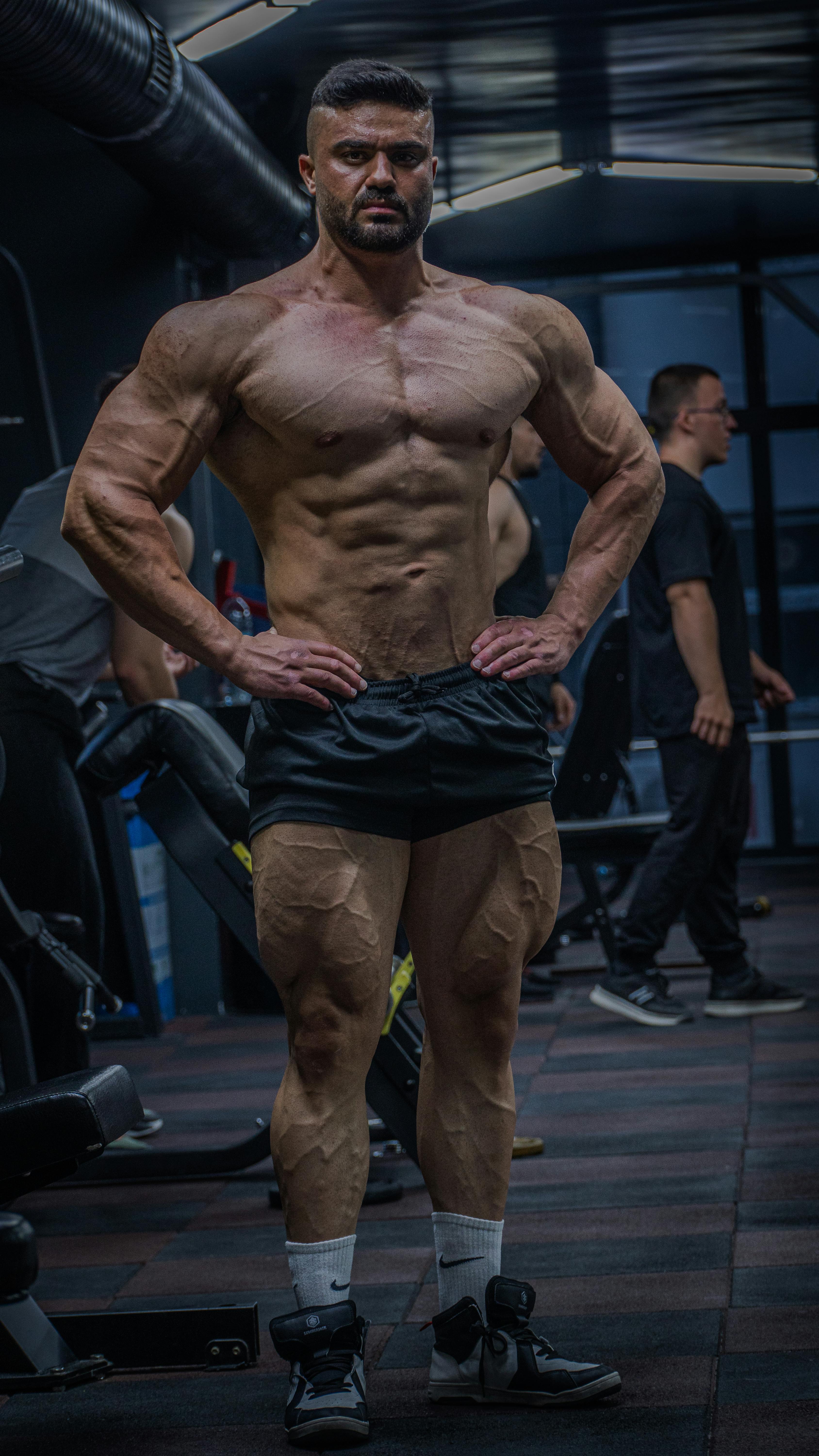 Muscular bodybuilder posing confidently indoors in a gym.