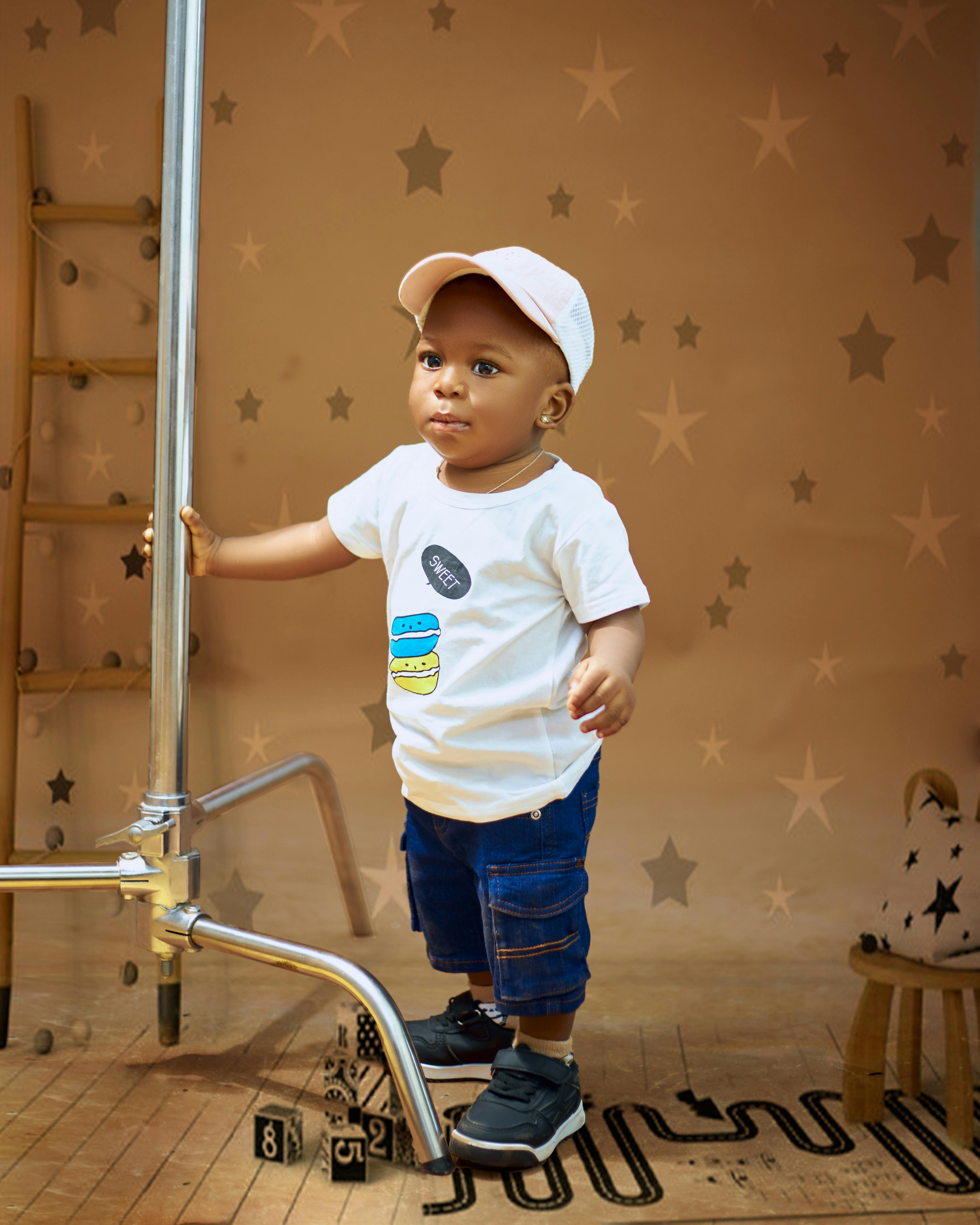 a baby boy standing on a ladder with a star on his shirt