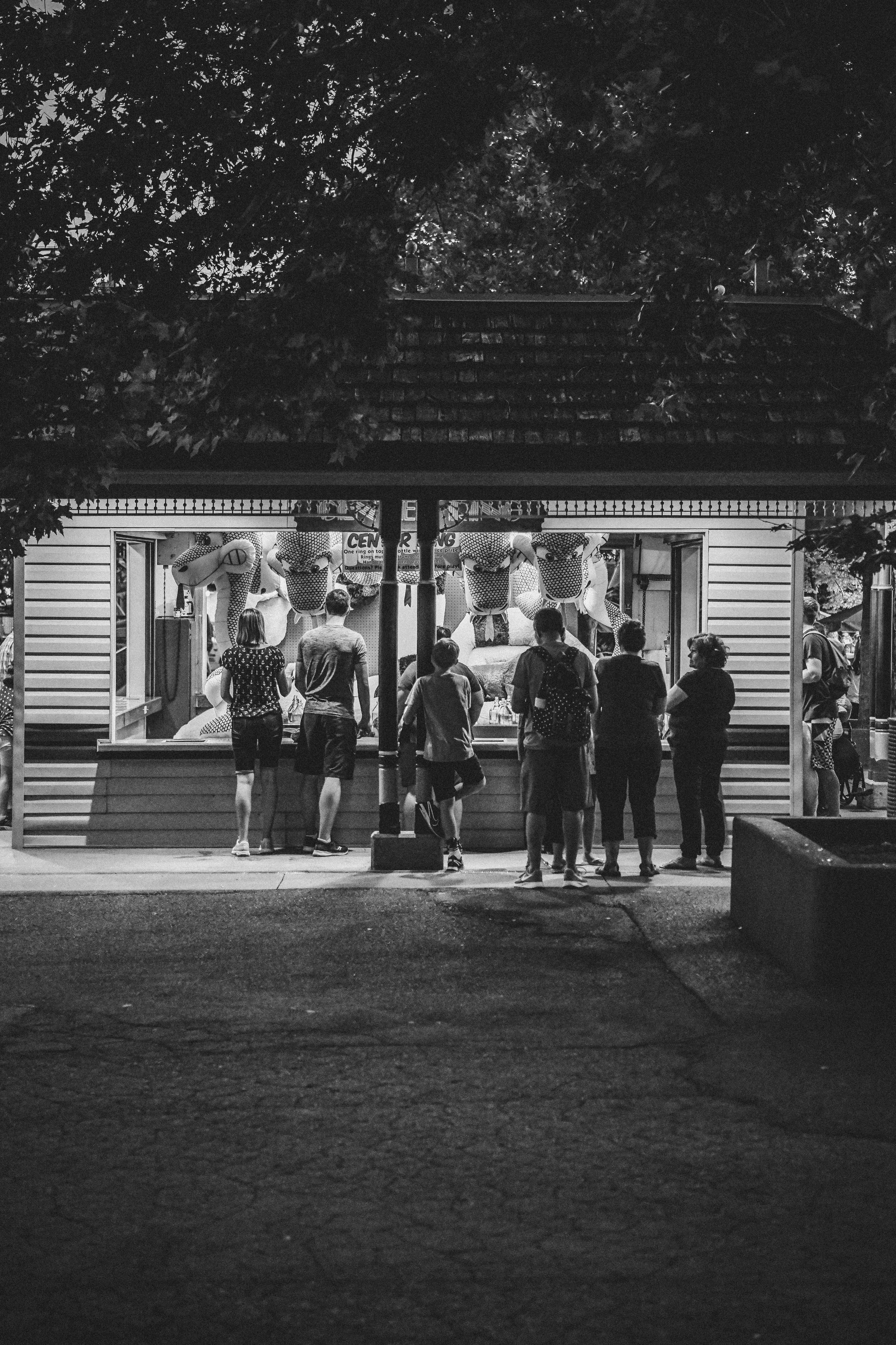 晚上，一群人聚集在灯火通明的市场摊位前，照片是单色拍摄的