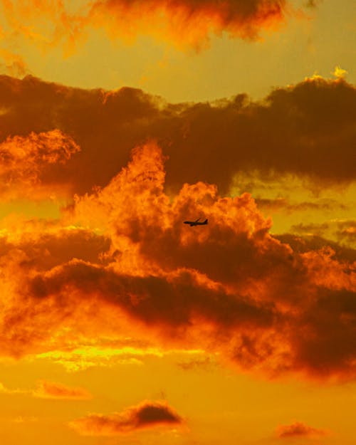 Silhouette of Flying Plane Under Cloudy Sky