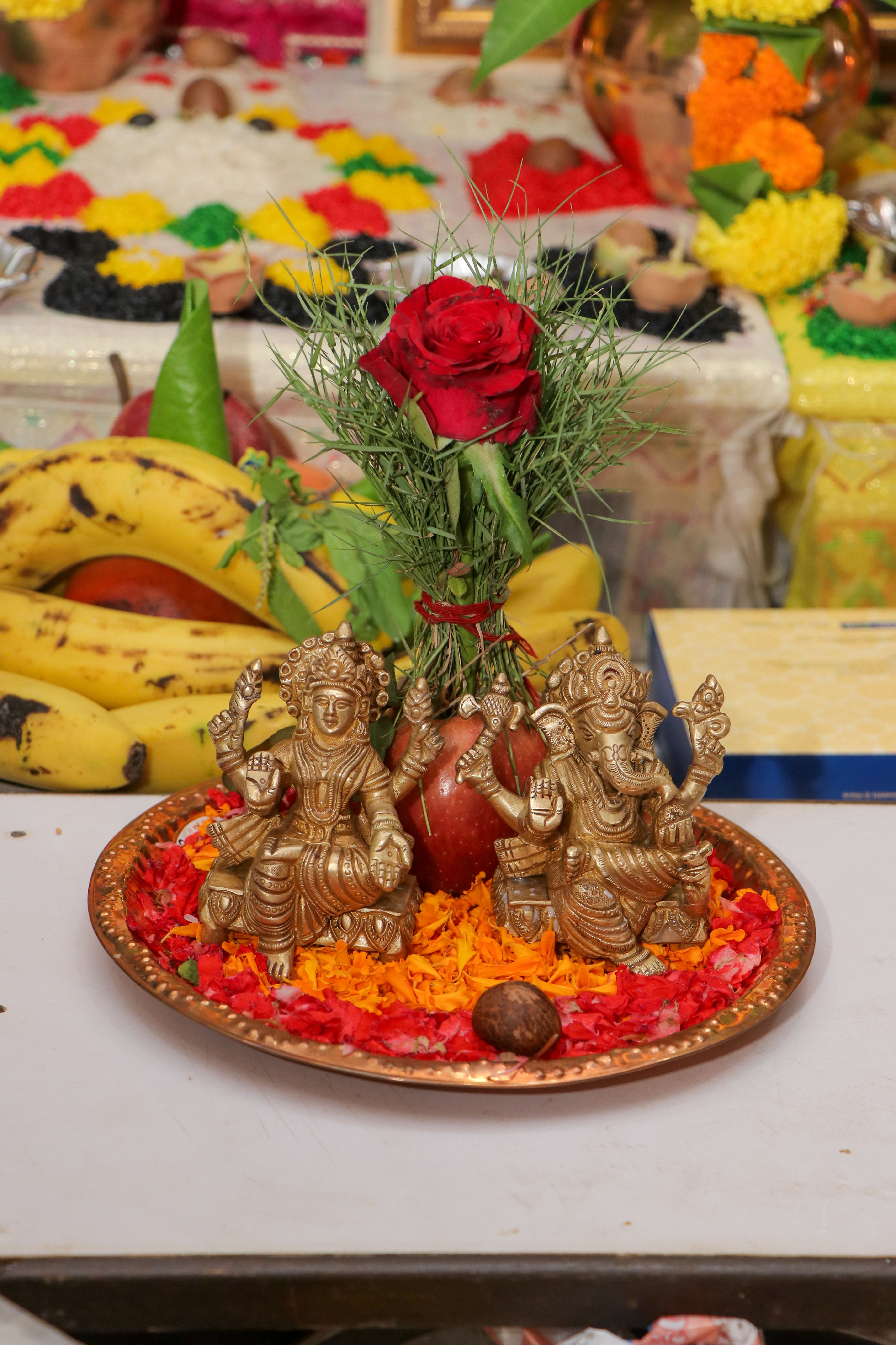 Vibrant Indian festival offering with deities, flowers, and fruit on a decorated plate.