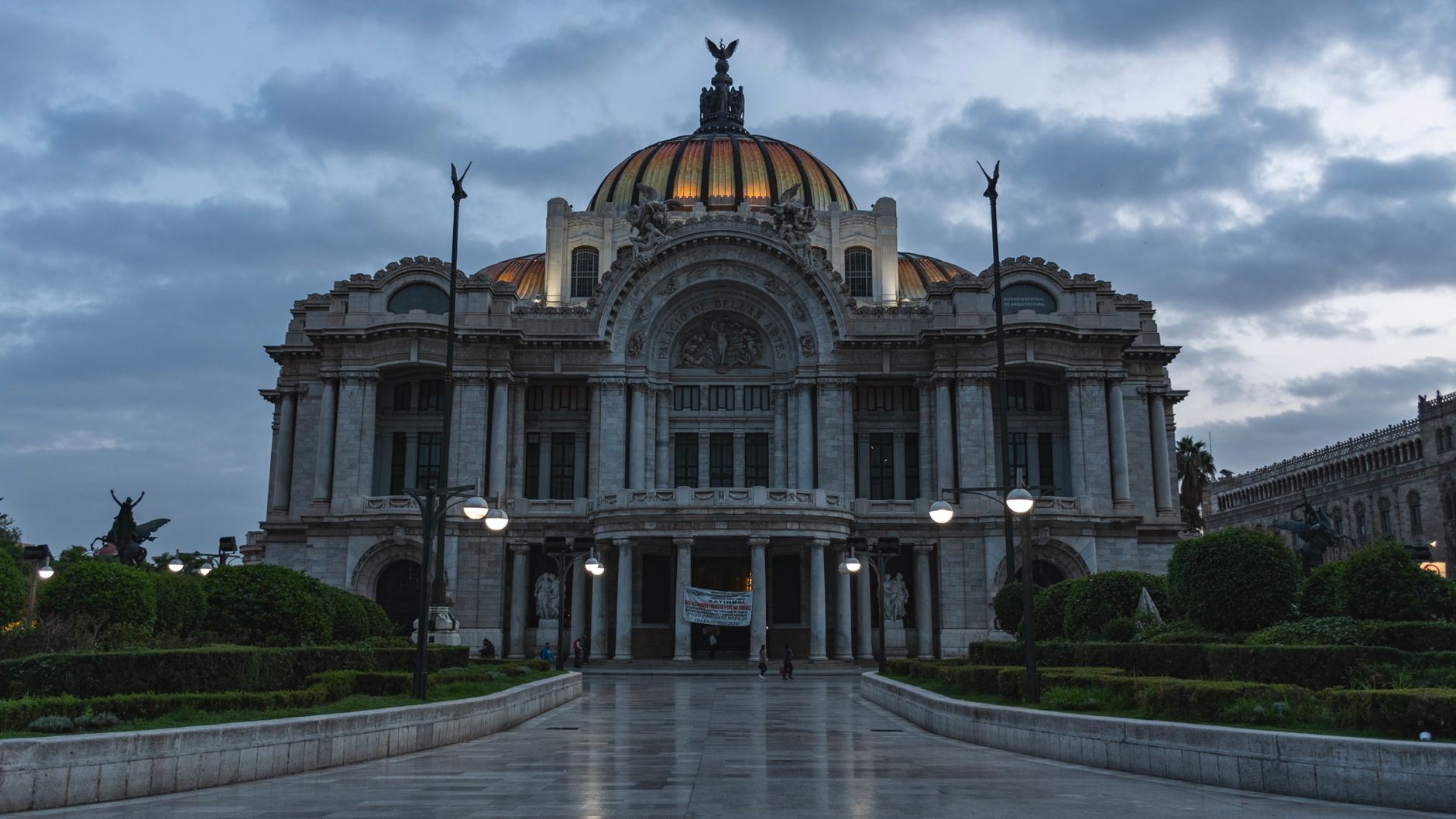 The Palacio de Bellas Artes lit at dusk under a dark sky