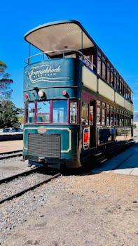 Experience the vintage charm of the Franschhoek double-decker tram under a clear blue sky.