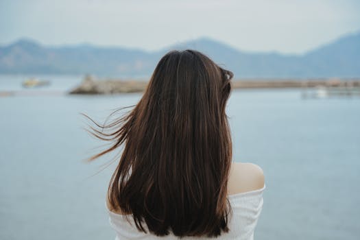 A serene image of a woman facing the ocean at a beach in Shenzhen, China during summer.