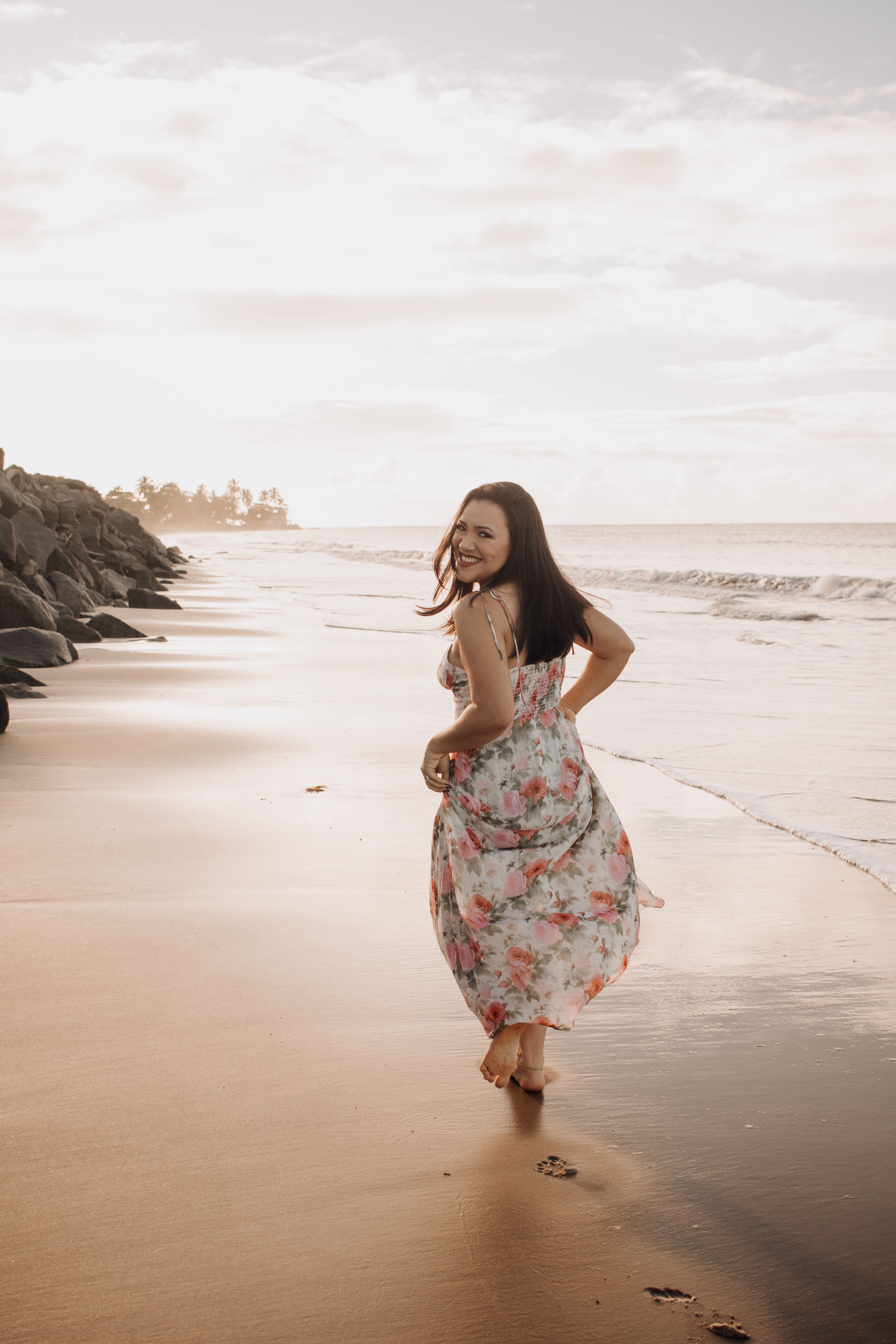 A woman in a floral dress walks along the beach · Free Stock Photo