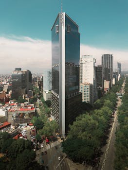 Aerial view of a towering skyscraper on Reforma Avenue in Mexico City with surrounding urban landscape.