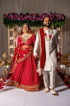 Bride and groom in traditional attire at a vibrant South Asian wedding.