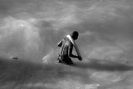 A man wading in the shallow waters of Barú beach with a float in black and white.
