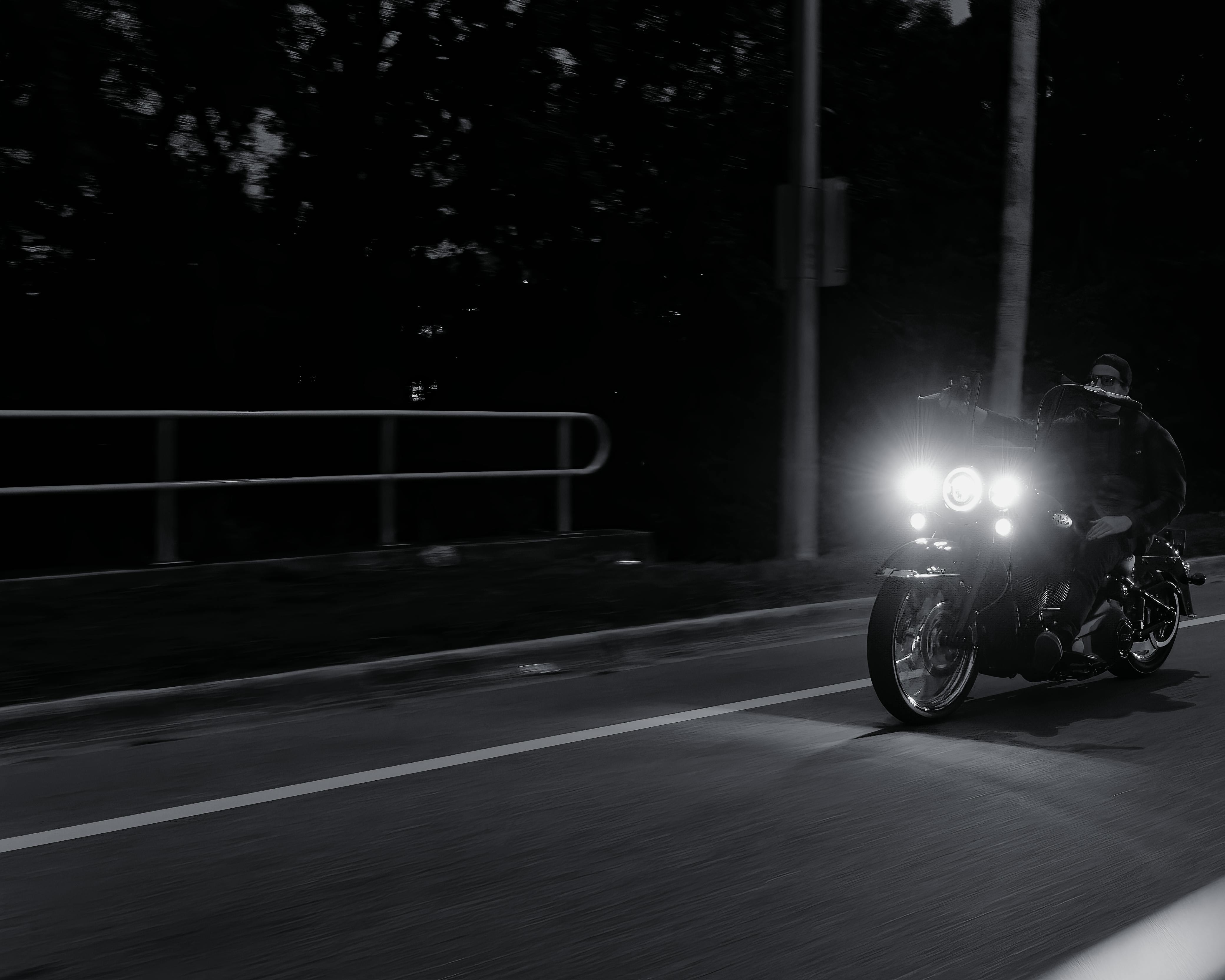 A biker speeds down the street on a motorcycle at night, captured in a panning shot.