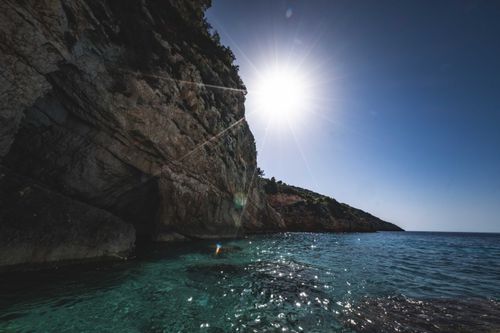 Free A stunning view of a cliff under the bright sun with clear blue sea waves crashing, showcasing nature's beauty. Stock Photo