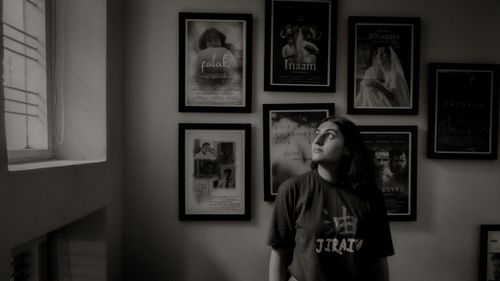 Free Black and white photo of a woman in an art gallery with framed portraits on the wall. Stock Photo
