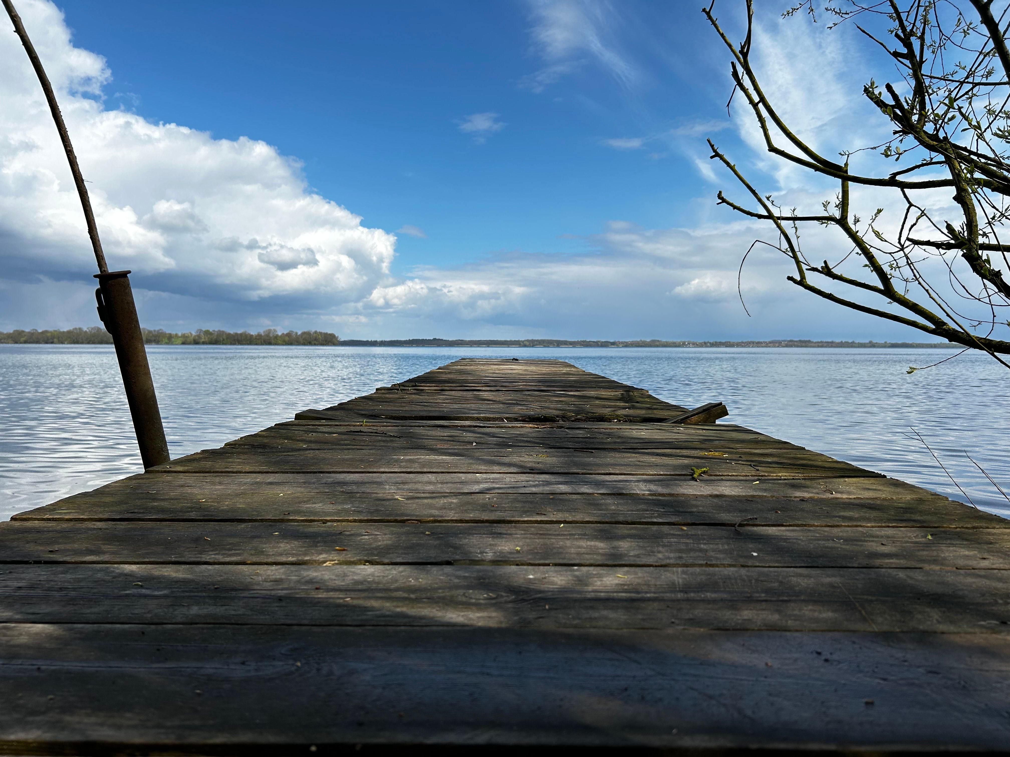 A wooden pier with a blue sky and clouds · Free Stock Photo