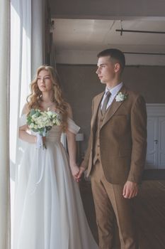 Bride and groom in stylish attire during an intimate indoor wedding photoshoot.