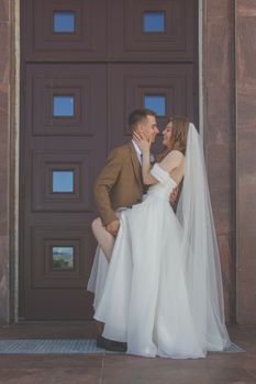 Bride and groom share a tender moment in front of an elegant doorway on their wedding day.