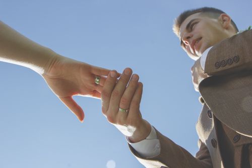 Free A man and woman holding hands outdoors under a clear blue sky, symbolizing unity and support. Stock Photo