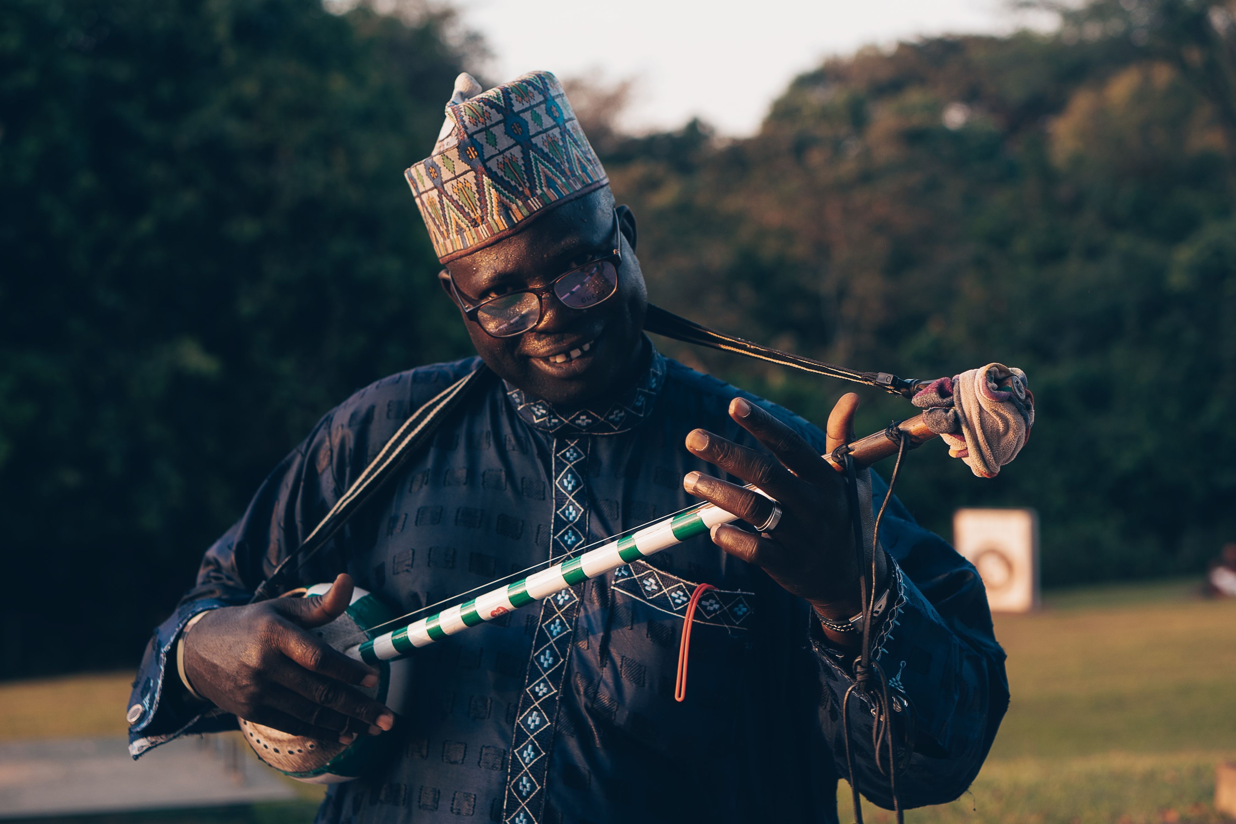 A joyful African musician plays a traditional string instrument in an outdoor setting, embracing cultural heritage.