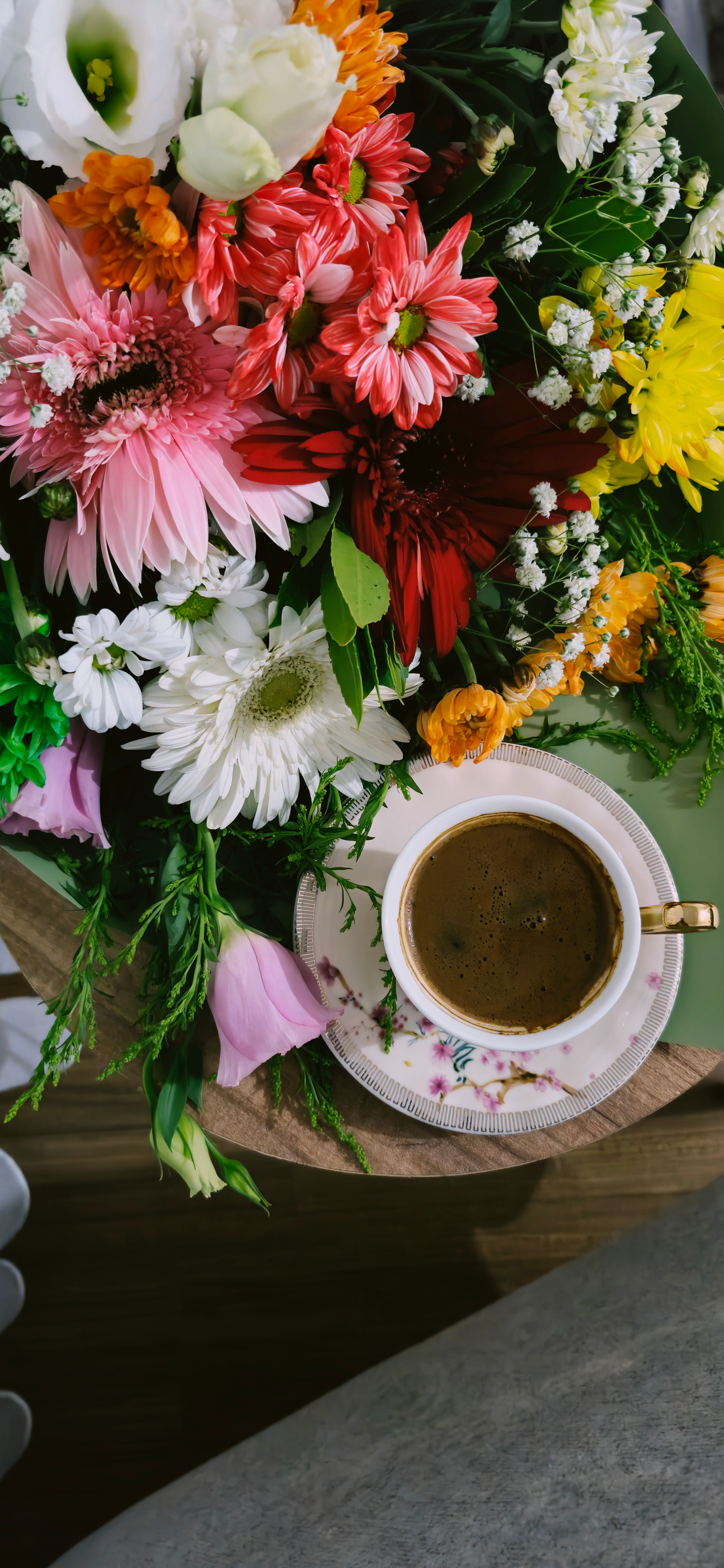 A coffee cup with flowers on top of a table · Free Stock Photo