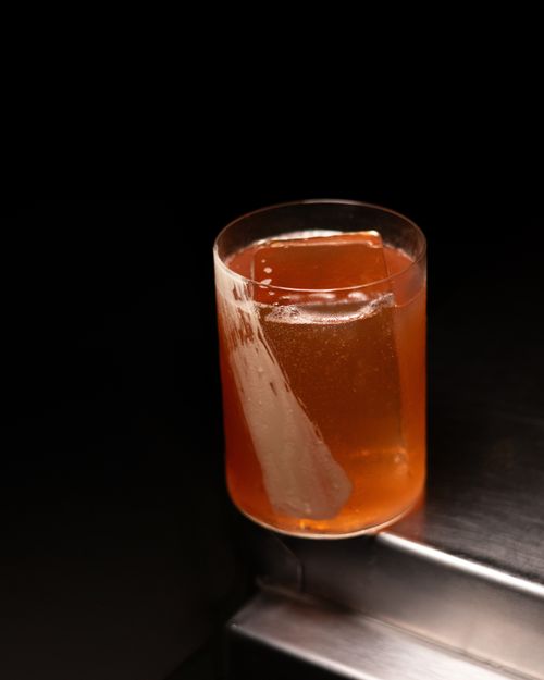 Free A sophisticated cocktail glass with a large ice cube, set against a black background for a refined look. Stock Photo