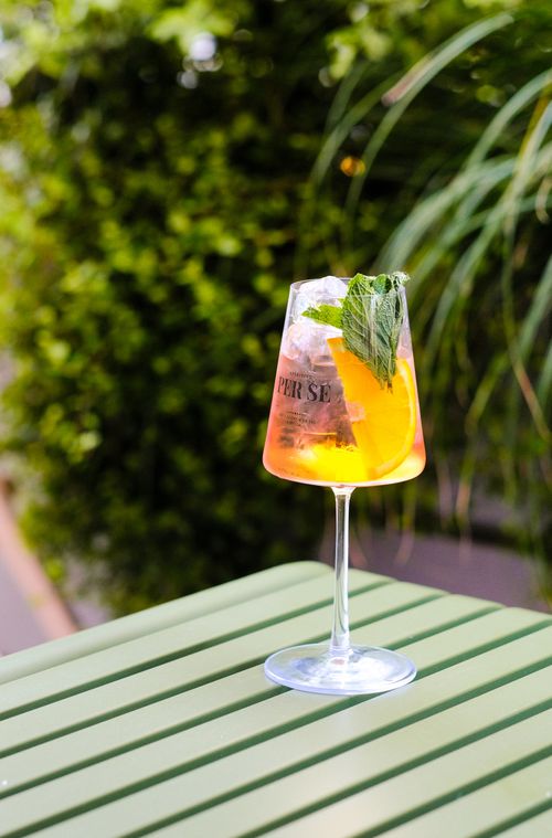 Free A vibrant Aperol Spritz with orange slice and mint, set outdoors on a summer day in Algarvia. Stock Photo