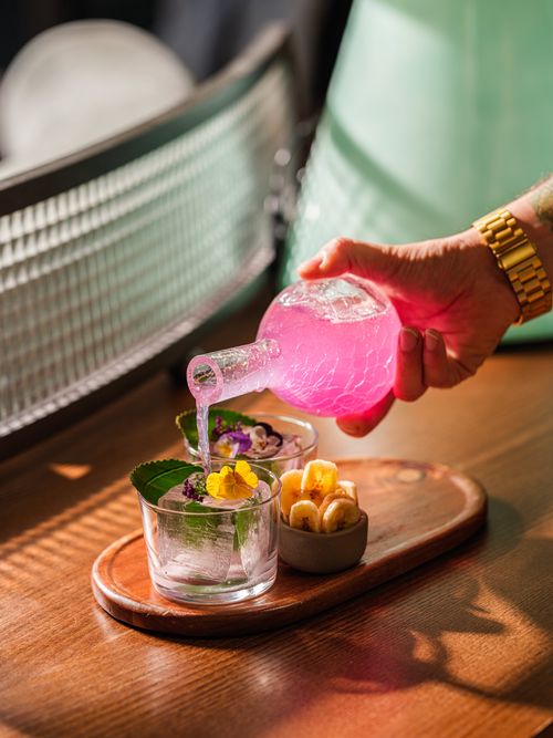 Free Elegant floral cocktail being poured with precision at a London bar, highlighting mixology creativity. Stock Photo