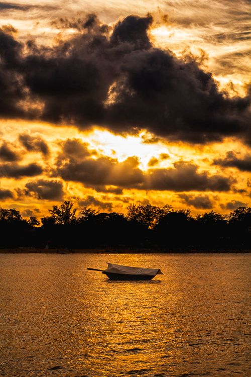 Free Serene scene of a boat on the water during a stunning Hải Phòng sunset with dramatic clouds. Stock Photo