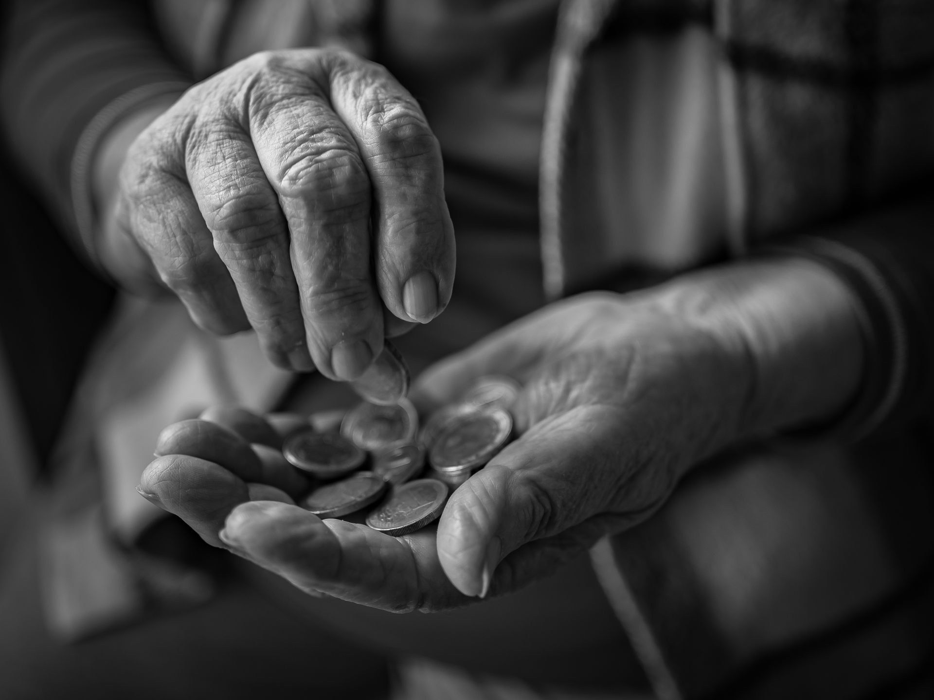 Primer plano de manos mayores contando monedas en una mesa cocina