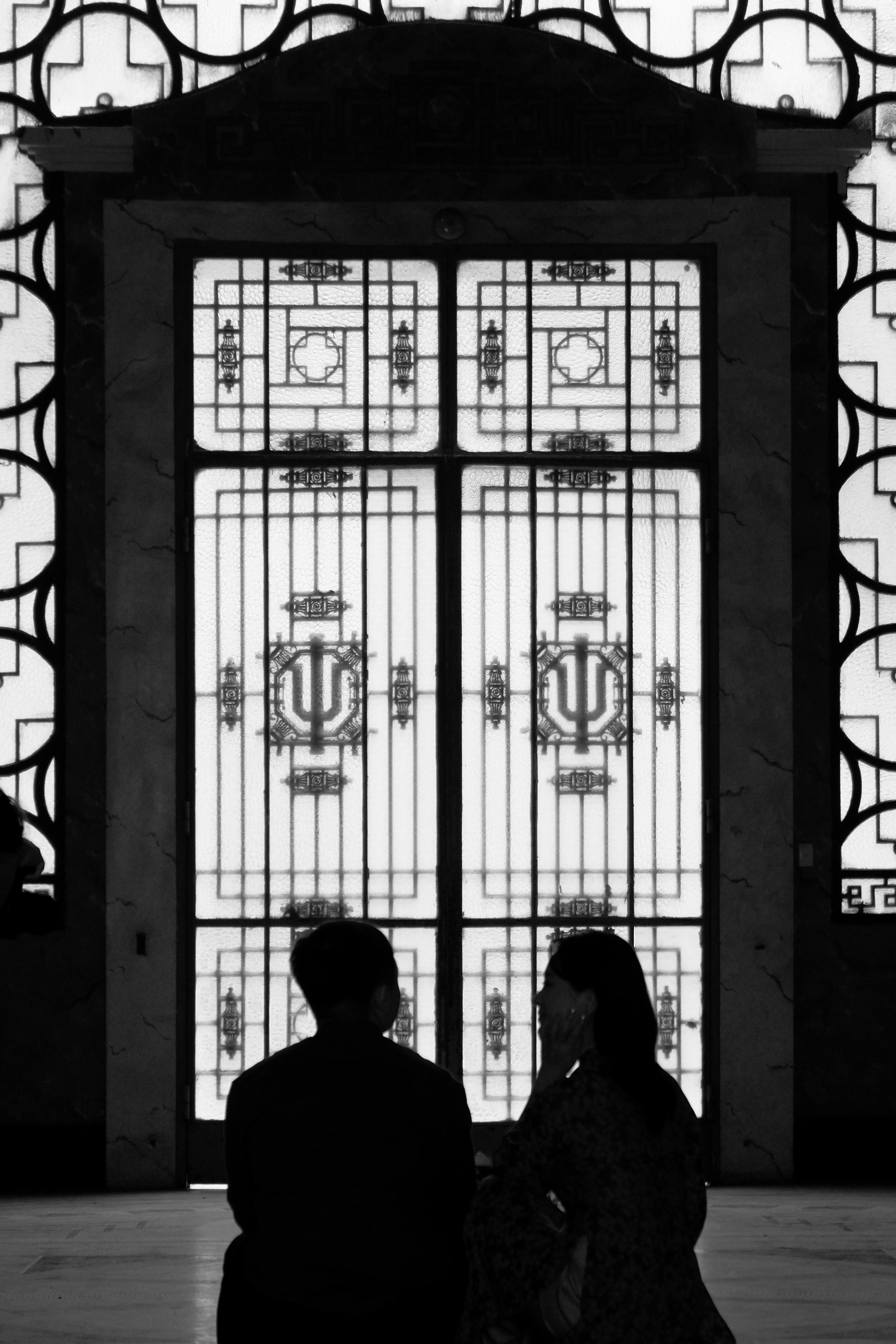 Silhouettes of two people in front of an artistic iron gate, creating a dramatic scene.