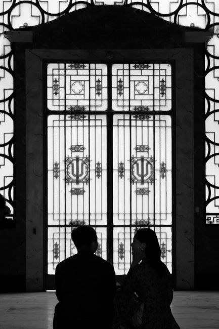 Silhouettes of two people in front of an artistic iron gate, creating a dramatic scene.