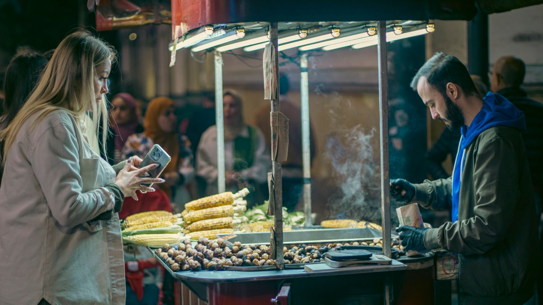 A phone showing a mobile money payment prompt beside a market stall till number
