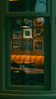 Warm cozy cafe interior with modern artwork and soft lighting through window view.