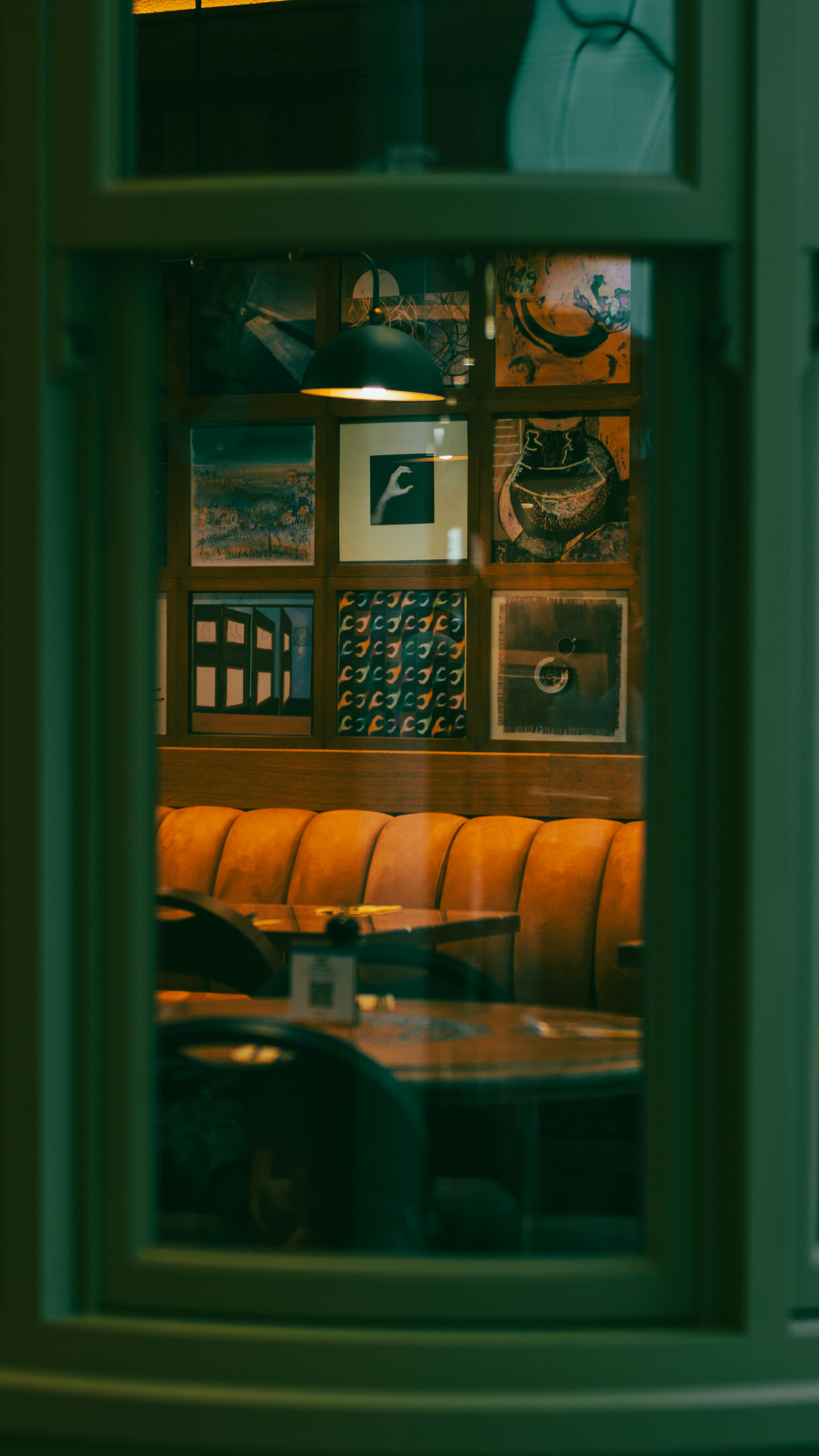 Free Warm cozy cafe interior with modern artwork and soft lighting through window view. Stock Photo