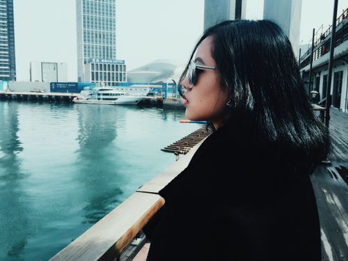 Free A woman in sunglasses gazes thoughtfully over a city harbor on a sunny day. Stock Photo