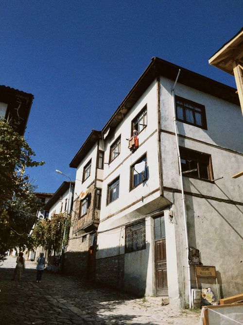 Free A picturesque street view of traditional townhouses with a vibrant blue sky overhead, showcasing timeless architectural style. Stock Photo