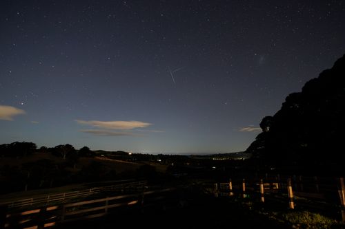 Free A serene night sky filled with stars and a silhouette of hills under soft moonlight. Stock Photo