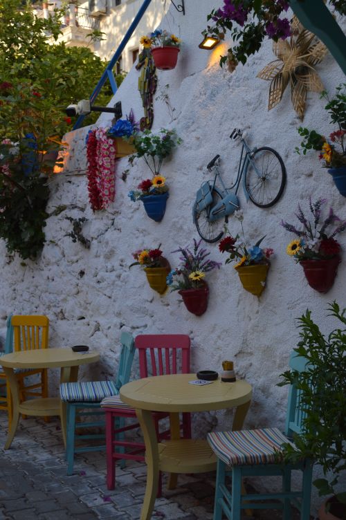 Free Colorful café setting with flowers and vintage decor against a rustic wall. Stock Photo