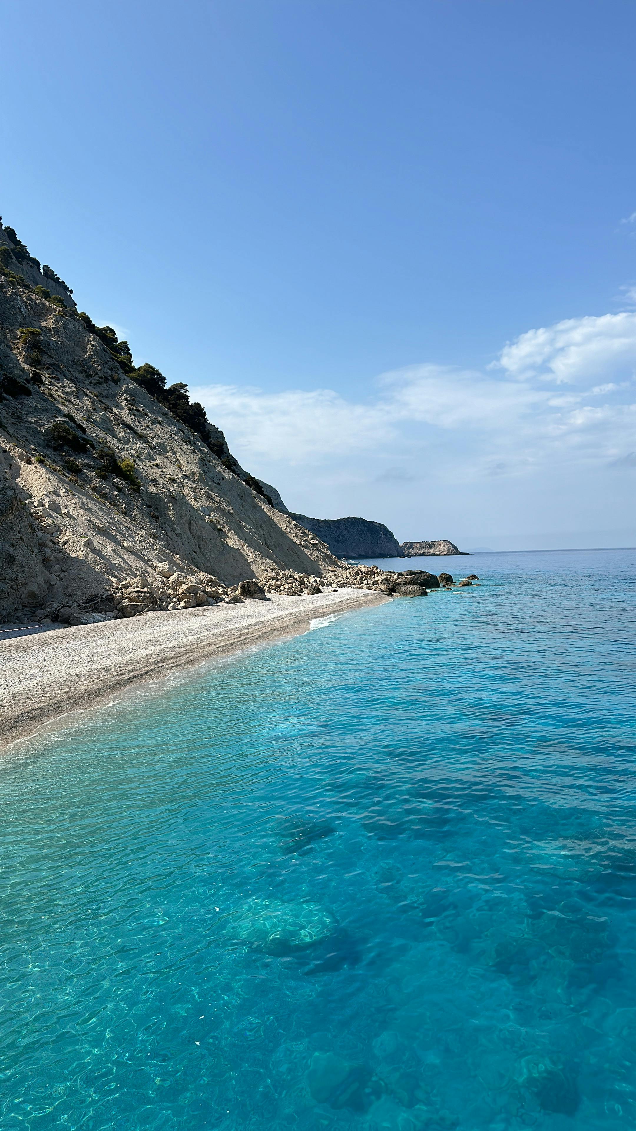 Breathtaking view of a pristine beach and clear turquoise ocean against steep cliffs.