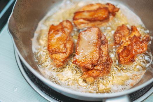 Close-up of golden fried chicken pieces sizzling in a hot pan for a delicious meal.