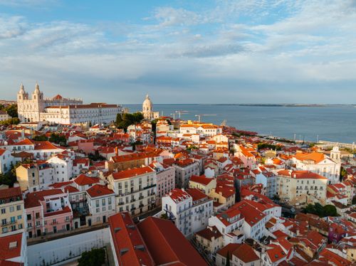 Free Stunning aerial photo of Lisbon's vibrant architecture and coastline at sunset. Stock Photo
